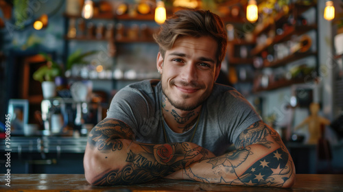 Smiling young man with tattoos leaning on hands at a bar.