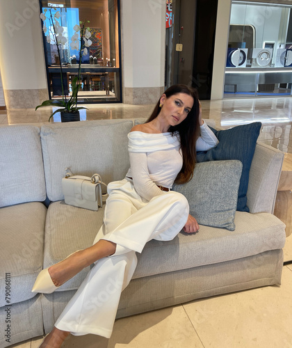 beautiful woman with dark hair in elegant clothes with accessories posing in luxury interiod of hotel hall photo