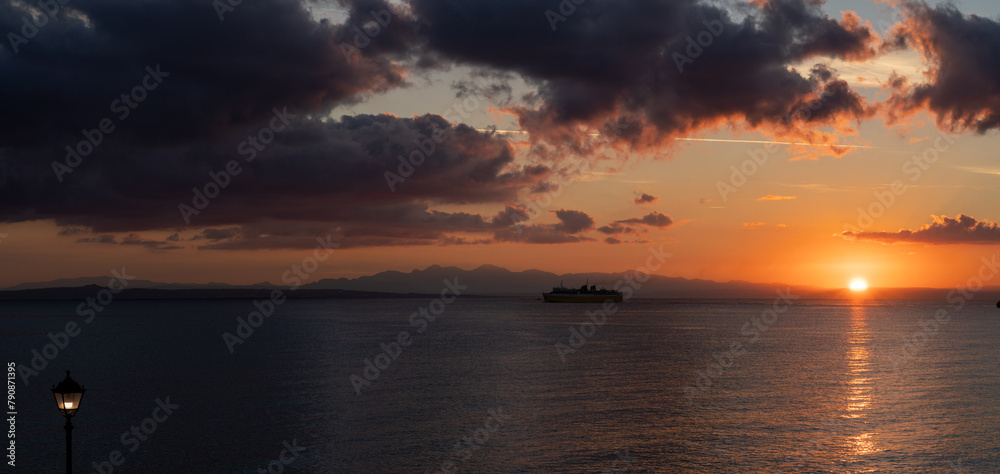 Panorama of a cruise ship voyage against calm dramatic clouds during sunrise in zante, Zakynthos, Greece