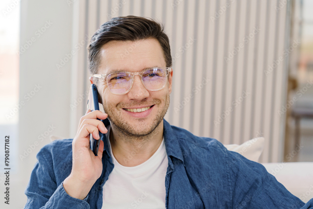 Affable professional in a smart-casual ensemble converses on a smartphone in a modern, well-lit interior. Affable professional in a smart-casual ensemble converses on a smartphone in a modern, well-lit interior.