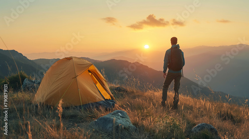 Climbers with backpacks relax on top of mountain and enjoy cliff sunrise with mountain scenery in the background. Sunny day and blue sky
