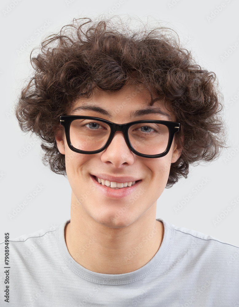 Smiling and handsome, the young man wears glasses. He looks into the camera with his blue eyes, man portrait with eyeglasses isolated against a gray background Smiling and handsome, the young man wears glasses. He looks into the camera with his blue eyes, man portrait with eyeglasses isolated against a gray background