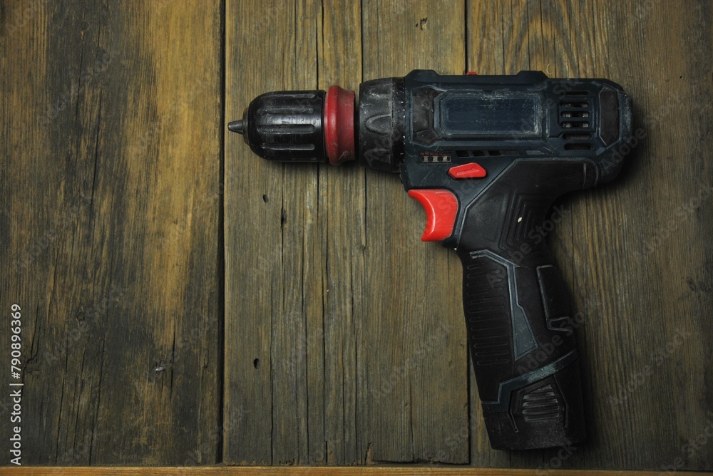 Cordless screwdriver, cordless drill on a wooden background. dark photo