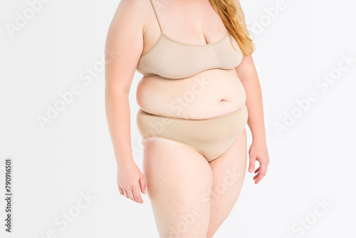 Fat woman in beige underwear on gray background, overweight female body, plastic surgery concept