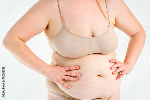 Tummy tuck, flabby skin on a fat belly, abdomen with obesity and cellulite, saggy stomach, plastic surgery concept on studio background