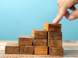 Costruire con successo - impilare a mano i blocchi di legno ,Disporre a mano dei blocchi di legno che salgono come una scala, simboleggiando la crescita e il successo.