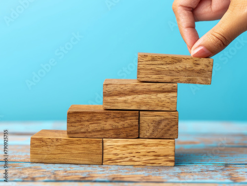 Costruire con successo - impilare a mano i blocchi di legno ,Disporre a mano dei blocchi di legno che salgono come una scala, simboleggiando la crescita e il successo. photo