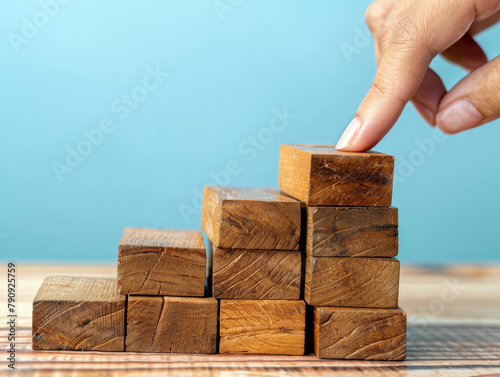 Costruire con successo - impilare a mano i blocchi di legno ,Disporre a mano dei blocchi di legno che salgono come una scala, simboleggiando la crescita e il successo. photo