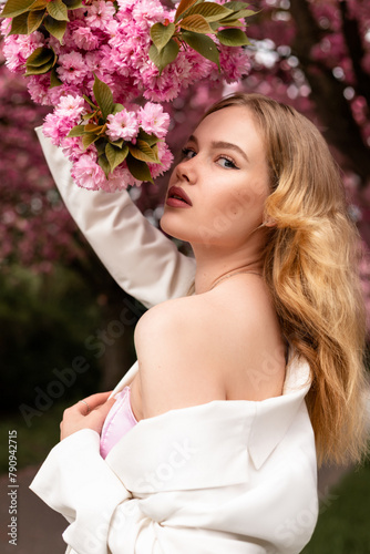 Attractive young woman standing near cherry blossoms. Sakura Alley