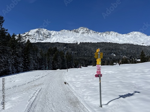 Hiking markings and orientation signs with signposts for navigating in the idyllic winter ambience above the tourist resorts of Valbella and Lenzerheide in Swiss Alps - Canton of Grisons, Switzerland