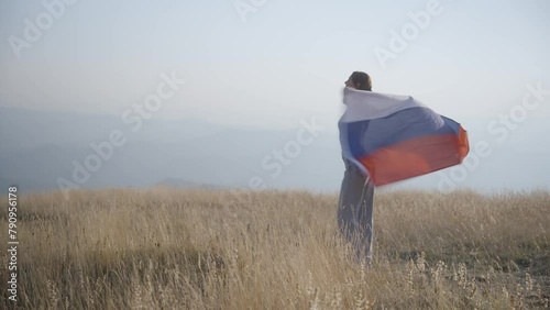 Russian woman with Russian flag,standing on top of mountain photo