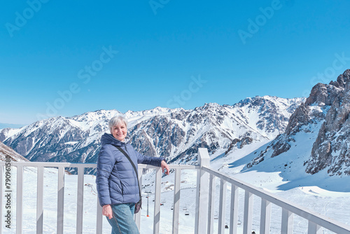 Senior woman on background of snowy mountains, Shymbulak ski resort, Almaty, Kazakhstan.