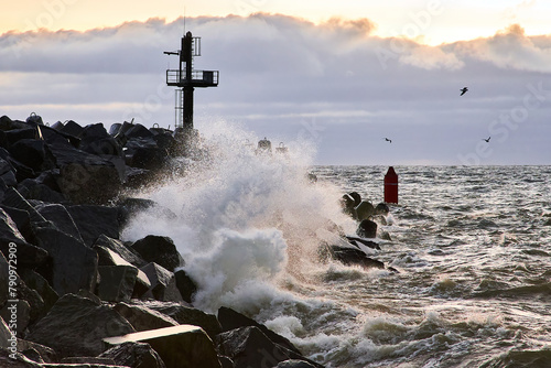 Seascape with a breakwater and a view of the water. Strong waves break against a protective structure made of concrete photo