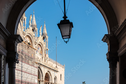Scenic view through an arch window on St Mark's Basilica in city Venice, Veneto, Northern Italy, Europe. Venetian architectural landmarks and antique lantern hanging from ceiling. Urban summer tourism