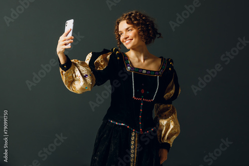 Portrait of a young aristocratic woman doing photo selfie with mobile phone and dressed in a medieval dress