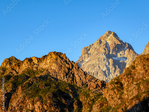 Scenic sunrise view of  mountain summit Monte Viso (Monviso) in the Cottian Alps, Piemonte, Italy, Europe. The rock walls of the Stone king are shining in warm red orange colors. Majestic landscape photo