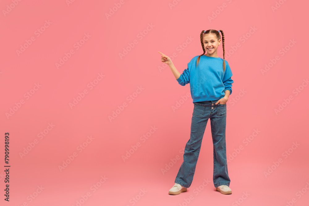 Happy girl pointing to side on pink background Happy girl pointing to side on pink background