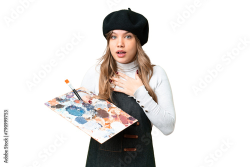 Young artist girl holding a palette over isolated chroma key background surprised and shocked while looking right