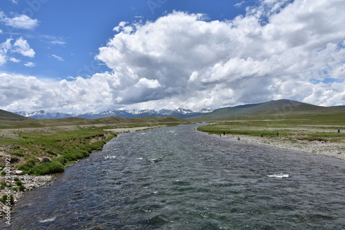 Breathtaking view of a river flowing through the vast deosai plains with mountains under a cloudy sky photo