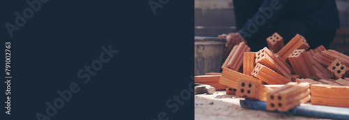 Worker hand laying bricks and using plaster trowel cement to build a house at construction site-banner image.