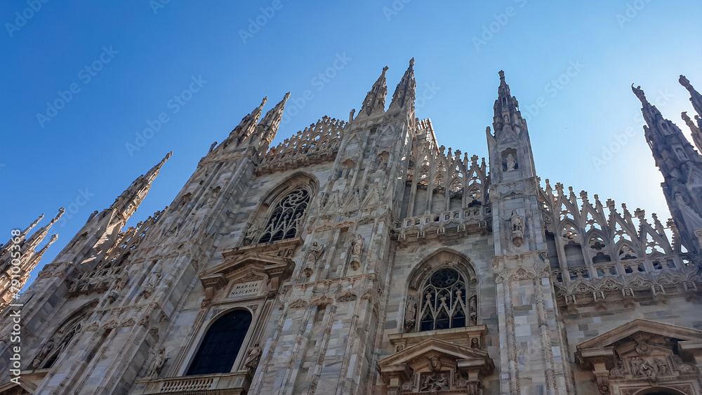 External view of Milan Cathedral (Duomo di Milano) from the Piazza del Duomo, Milan, Lombardy, Italy, Europe. Historical marble facade with spires. Gothic architecture features. City travel tourism