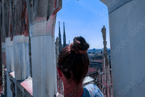 Female tourist with external view of Milan Cathedral (Duomo di Milano) from the Piazza del Duomo, Milan, Lombardy, Italy, Europe. Historical marble facade with spires. Gothic architecture features