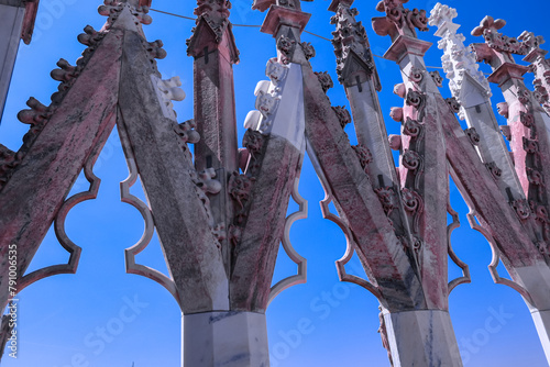 View of isolated marble statue of the Milan Cathedral (Duomo di Milano) seen from rooftop, Milan, Lombardy, Italy, Europe. Historical facade with spires. Gothic architecture features. Blue background