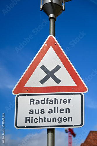 Verkehrswende - Radfahrer aus allen Richtungen, Straßenschild für Kreuzung, Rechts vor Links, Achtung Fahrradverkehr, blauer Himmel