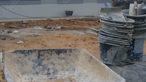 Powder Cement and sand mixing bucket tank, trowel, and plastering equipment in construction site.