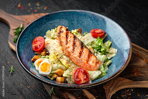 Tender salad with iceberg and grilled salmon fillet. Menu for a pub on a dark background. Colorful juicy food photography.
