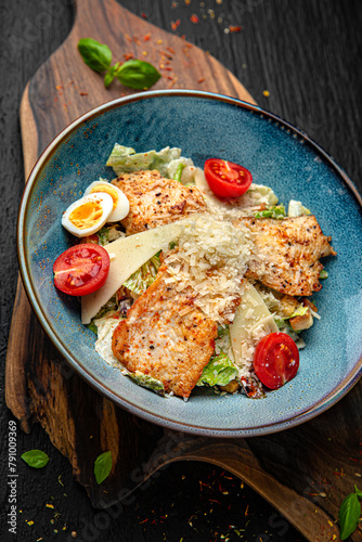 Tender salad with iceberg, chicken breast, parmesan and quail eggs. Menu for a pub on a dark background. Colorful juicy food photography.