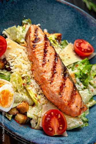 Tender salad with iceberg and grilled salmon fillet. Menu for a pub on a dark background. Colorful juicy food photography.