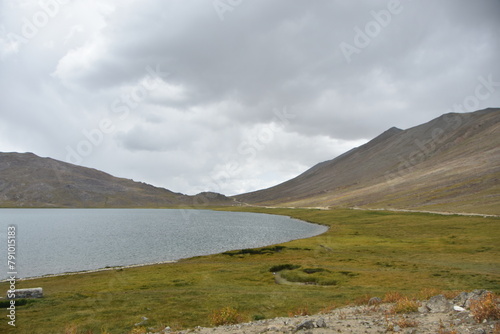 Tranquil high-altitude lake with mountainous backdrop under cloudy skies