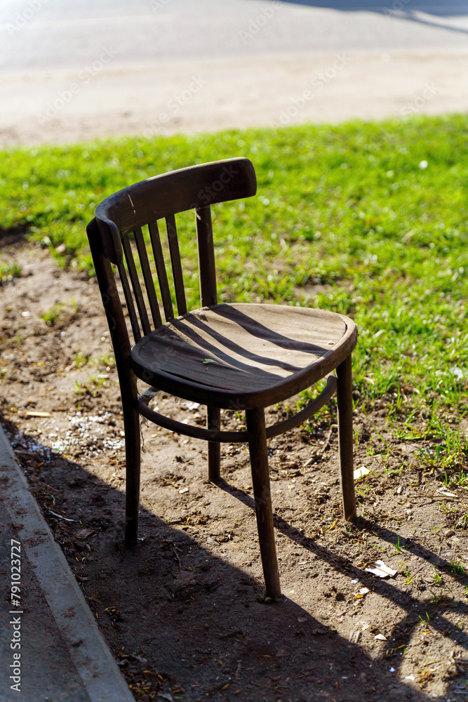 A very old wooden chair stands on the ground