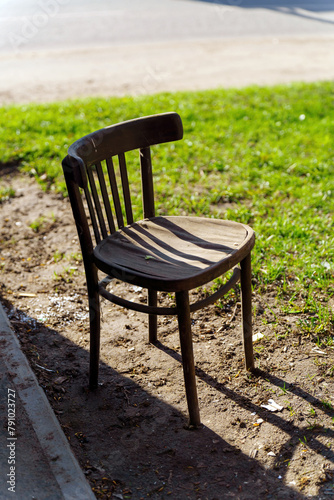 A very old wooden chair stands on the ground © Tatiana