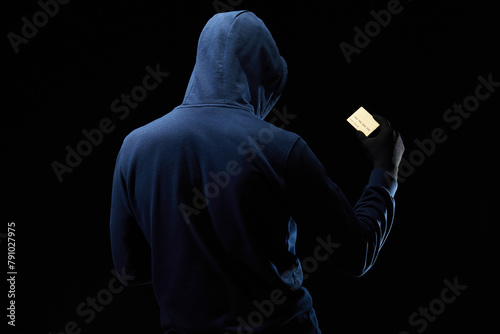 The hacker holds a credit card in his hand. Theft of personal data of credit cards. Digital cybercrime. An online criminal uses a stolen credit card.