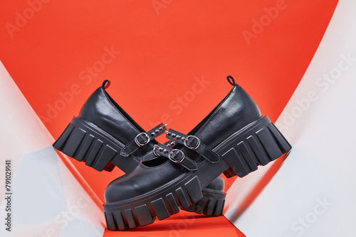 Black woman shoes on the red background. A pair glamour footwear with high soles. Trendy student shoes.