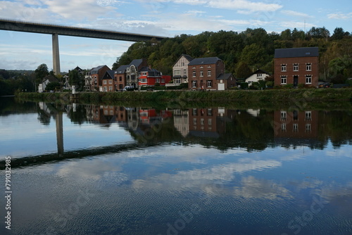 view of the town of Dinant in Belgium on the Meuse river with mirror reflection of buildings and bridge