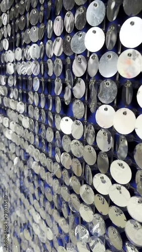 Vertical close-up of a shimmering wall made of metallic discs, industrial aesthetic suitable for modern designs