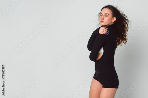 attractive slender white woman with curly brown hair poses in closed position on white background in the studio