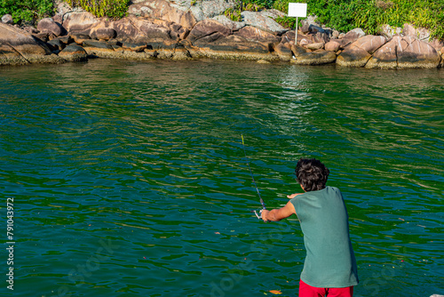 menino pescando na margem do canal que vem do mar em Florianópolis, Brasil photo