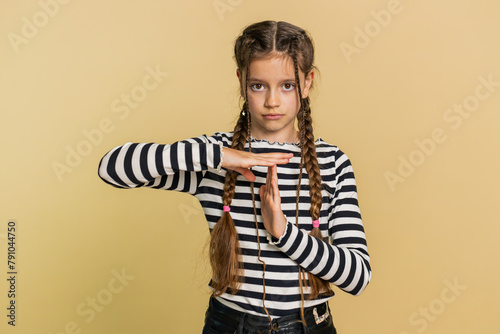 Tired serious upset young preteen child girl kid showing time out gesture, limit or stop sign, no pressure, I need more time, take a break, relax, rest, help. Teenager children on beige background