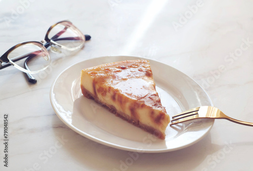 Piece of cheesecake with caramel in a plate on a marble table