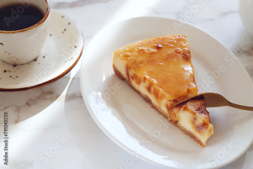 Piece of cheesecake with caramel in a plate on a marble table