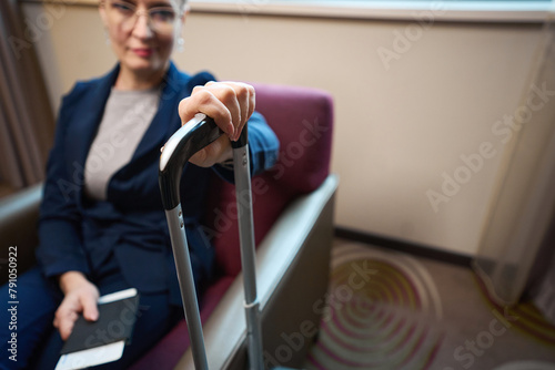 Focus on on foreground of hand of blurred businesswoman on suitcase