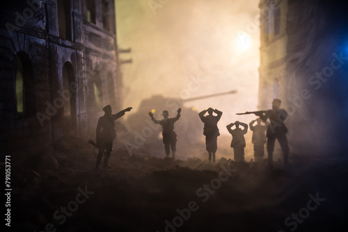 Military silhouettes fighting scene on war fog sky background. A German soldiers raised arms to surrender. Plastic toy soldiers with guns taking prisoner the enemy soldier.