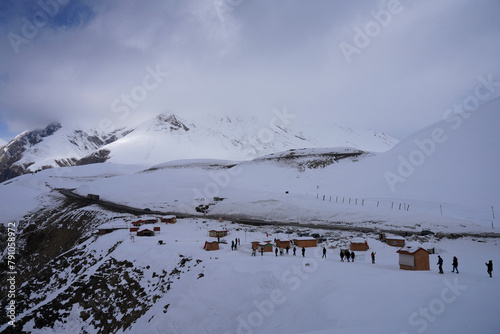 A group of tourists in small wooden huts stand on the snowcovered mountain, Devil's Valley in the Caucasus mountains, Gudauri, Georgian Military Highway, Georgia photo