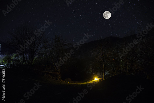 Mountain Road through the forest on a full moon night. Scenic night landscape of country road at night with large moon