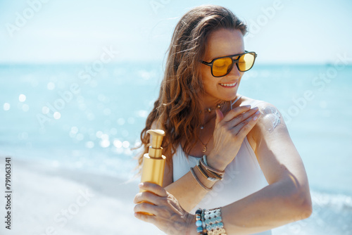 smiling stylish female on seacoast with sunscreen