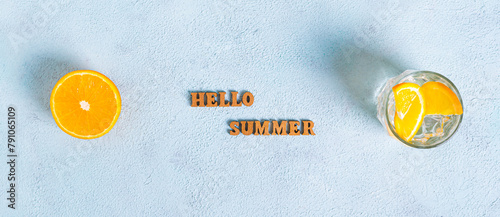Concept hello summer text, hat, cocktail and half an orange on blue background top view web banner